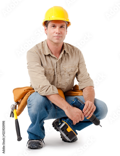 Full-length construction worker contractor carpenter squatting kneeling in hard hat with tools isolated on white background