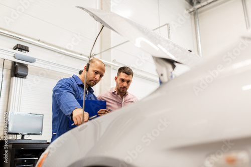 auto mechanic with clipboard and man at car shop