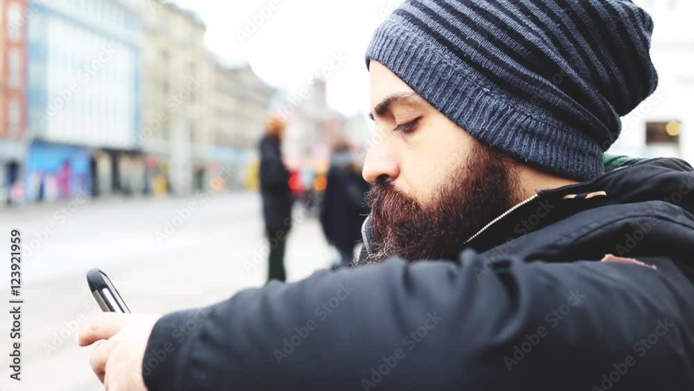 portrait of long bearded millennial bald man using a smartphone connected online, looking downward the screen, technology and social network concept portrait of long bearded millennial bald man using a smartphone connected online, looking downward the screen, technology and social network concept