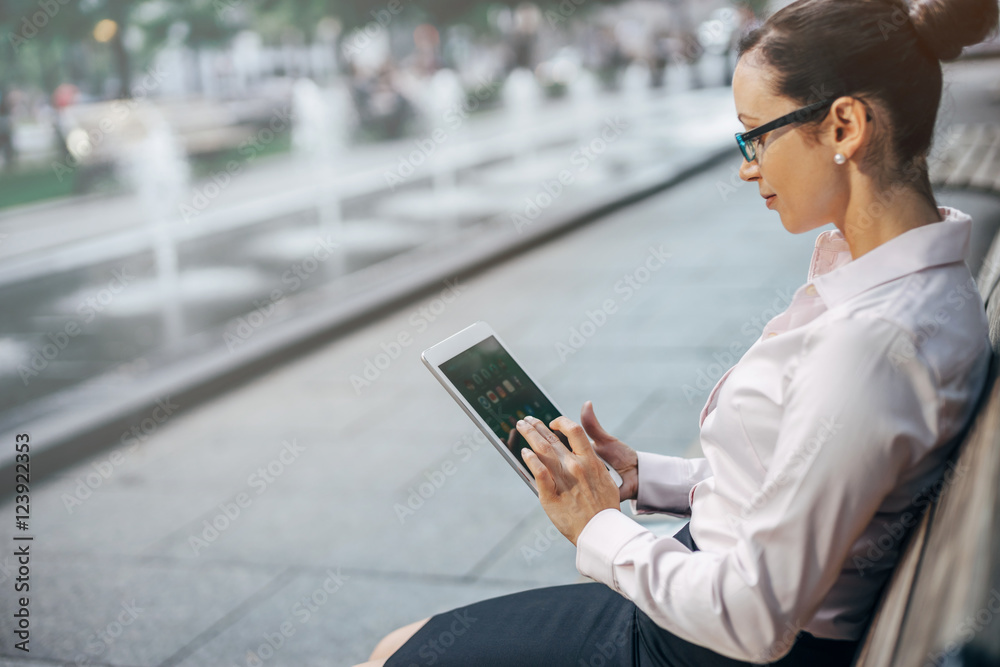 Woman searching information at internet via tablet pc outdoor, Business woman working on a new project and using modern tablet outdoor, blurred background, shallow DOF Woman searching information at internet via tablet pc outdoor, Business woman working on a new project and using modern tablet outdoor, blurred background, shallow DOF