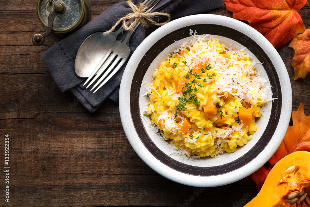 Fotografie Pumpkin risotto with thyme and parmesan cheese against dark wooden background