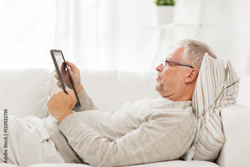 senior man with tablet pc lying on sofa at home senior man with tablet pc lying on sofa at home
