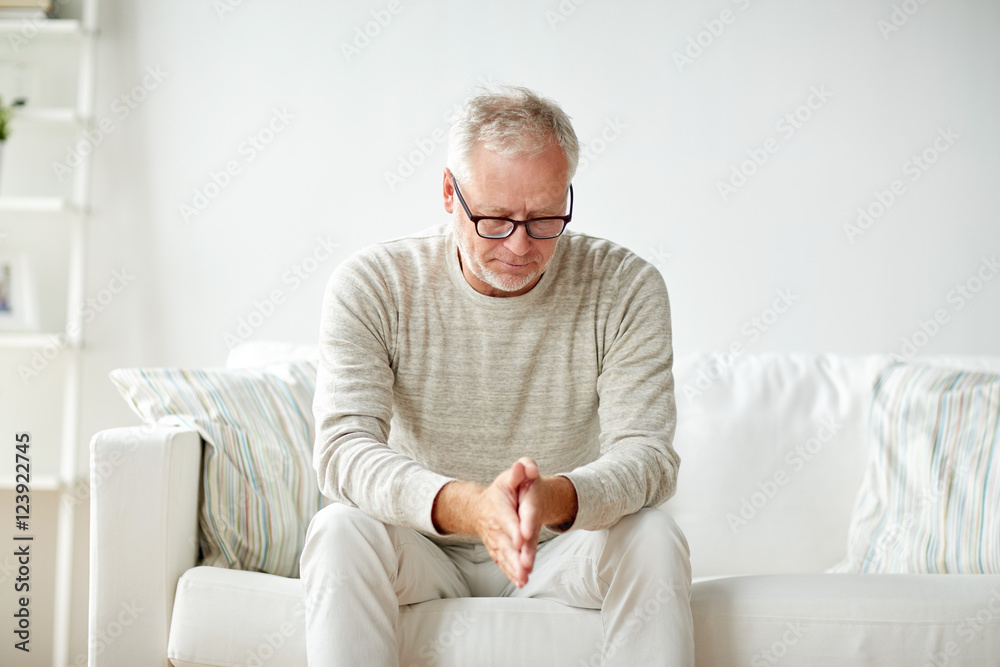  senior man sitting on sofa at home and thinking