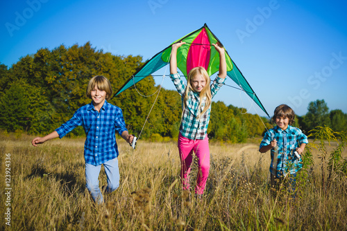 Group of happy and smiling kids playingin with kite outdoor