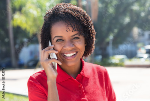 Laughing african american woman talking at mobile phone in city