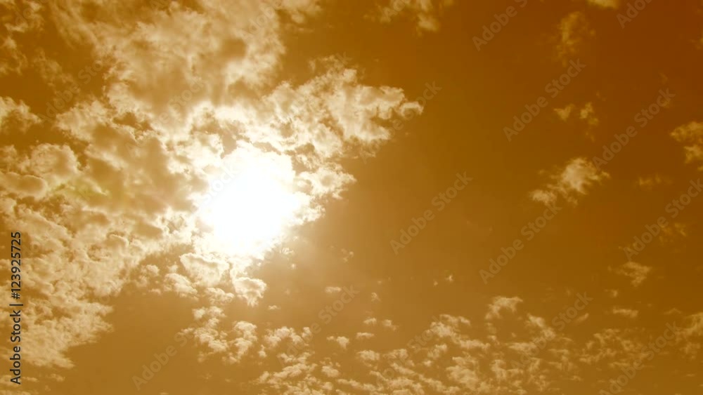 4K warm color treated cloudscape timelapse with clouds passing and sun shining through.