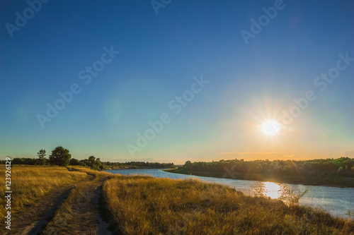 Landscape with river and dirt road to sunset time