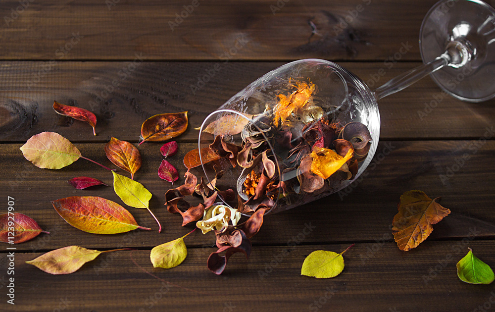 Autumn leaves in a wine glass on wooden table background