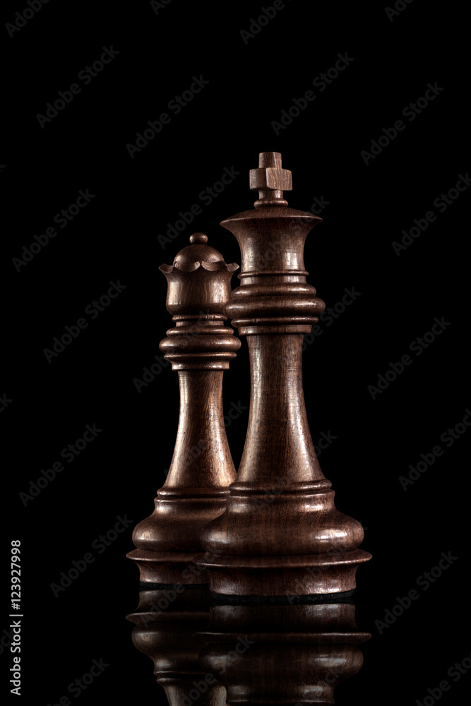 Powerful figures / Chess game concept of black wooden king and queen, the most powerful figures standing together against dark background. Powerful figures / Chess game concept of black wooden king and queen, the most powerful figures standing together against dark background.