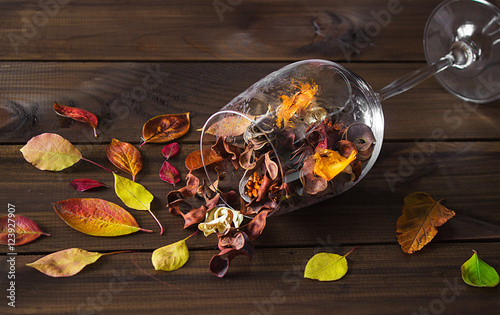 Autumn leaves in a wine glass on wooden table background