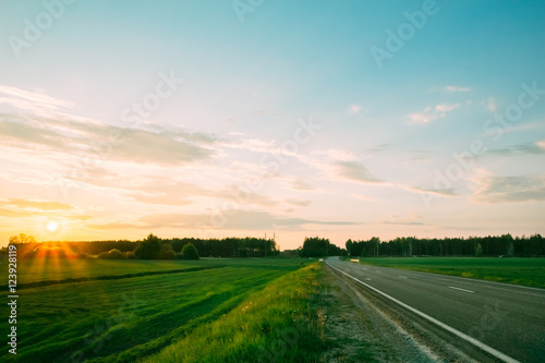 Sunset on a background of green fields and roads