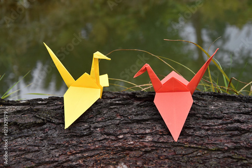 Origami paper in Nature, crane on a tree trunk.