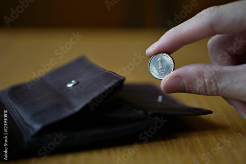 Male hand holding one Israeli Shekel (also Israeli new Sheqel, ILS or NIS ) and withdrawing that from the brown leather wallet