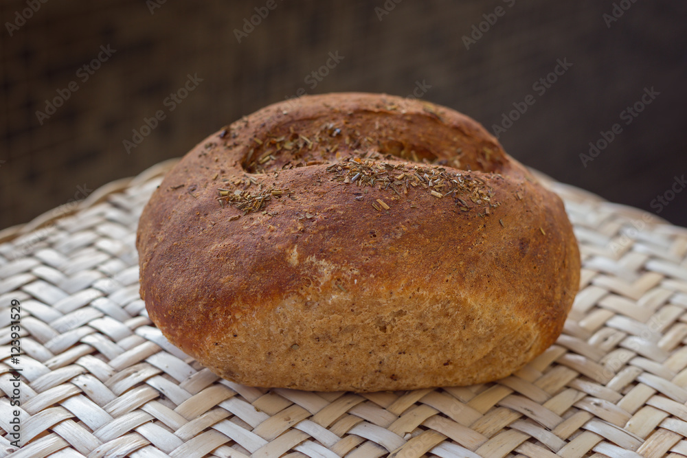 Loaf of rye bread homemade with herbs. one whole loaf of fresh bread lies on a wicker table. Loaf of rye bread homemade with herbs. one whole loaf of fresh bread lies on a wicker table.