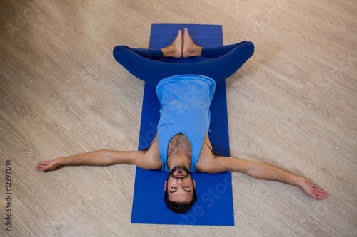 Bilde på lerret Man doing reclining bound angle pose on exercise mat