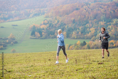 Beautiful young couple running in sunny autumn nature.