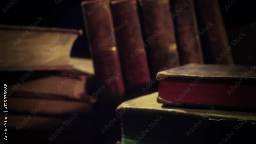 Old, aged books in a row on a wooden table. Camera panning and moving. Closeup.