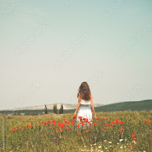 Beautiful young woman in the poppy field
