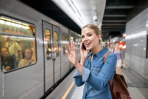 Woman making phone call at the underground platform, waving