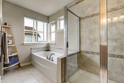 Glass shower and white bathtub in clean bathroom interior.