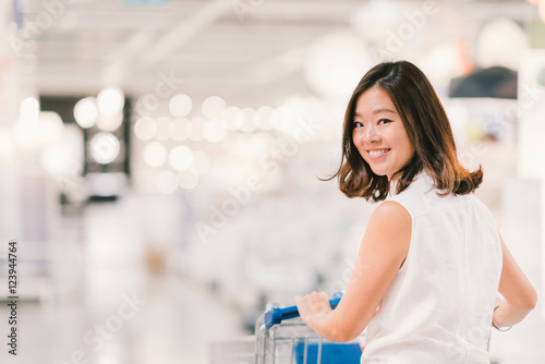 Beautiful young Asian woman smiling, with shopping cart, shoppin