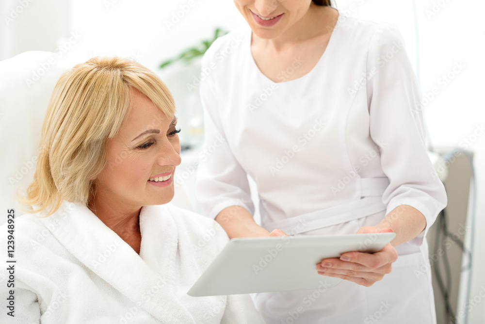 Skillful cosmetician consulting mature lady Skillful cosmetician consulting mature lady