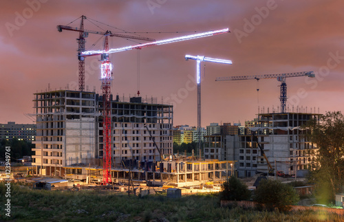 Lots of tower cranes build residential buildings at evening