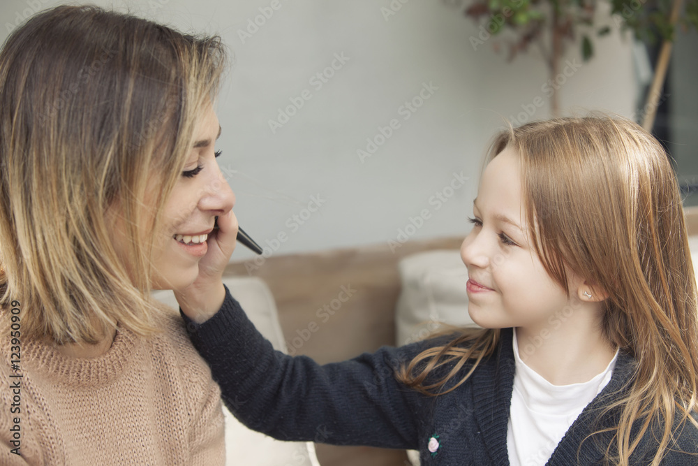 Mother and daughter playing with makeup.