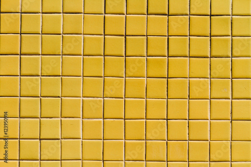 A wall surface with small yellow tiles