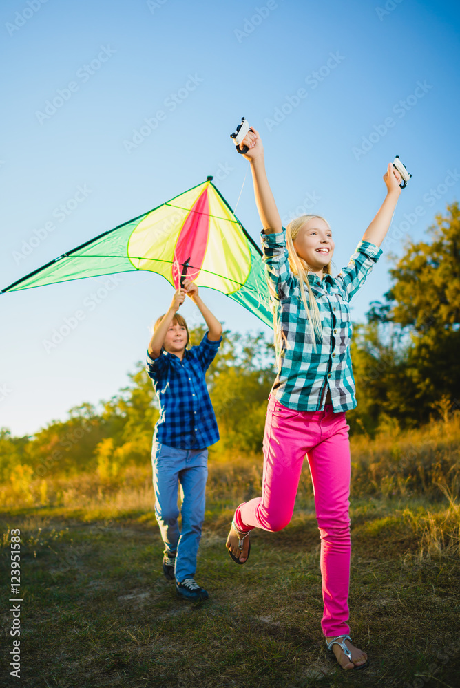 Fototapeta premium Group of happy and smiling kids playingin with kite outdoor