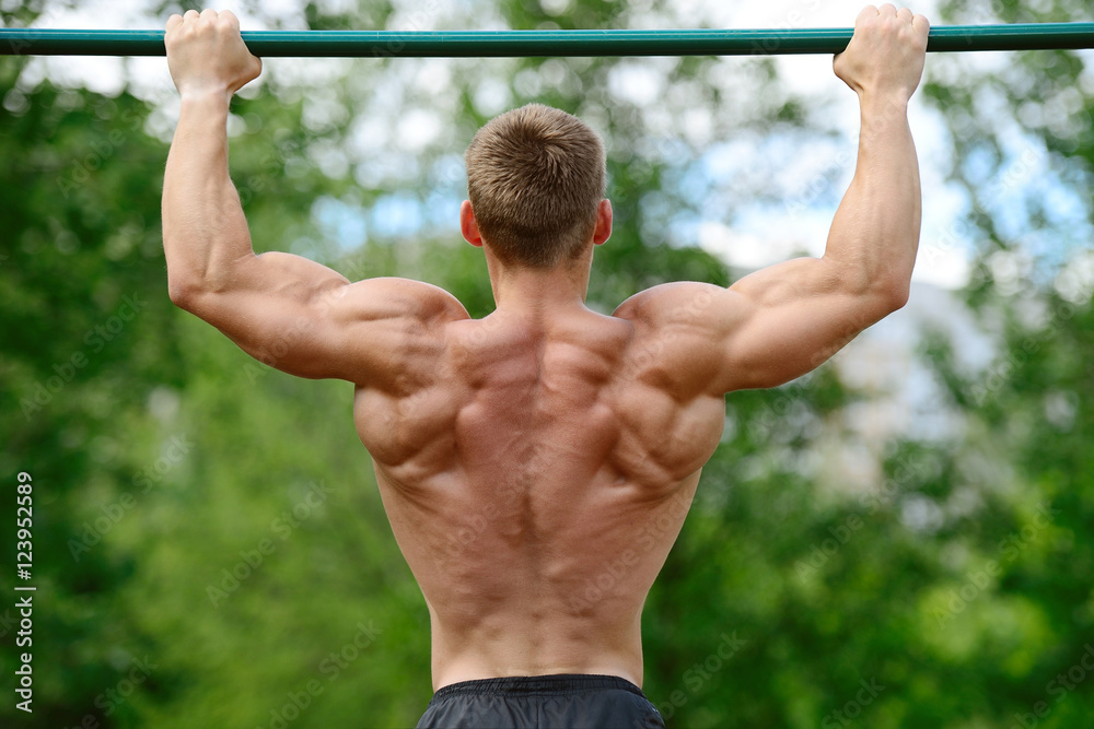 Muscular man practice street workout in an outdoor gym Muscular man practice street workout in an outdoor gym