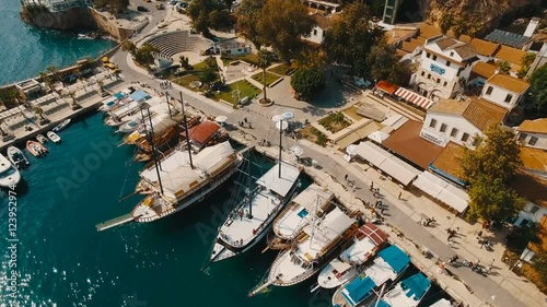 Aerial View of the Old Sea Port Where Many Ships, Boats and Yachts Stay, Tourists Walk Around. Sunny Day, Shot in 4K UHD photo