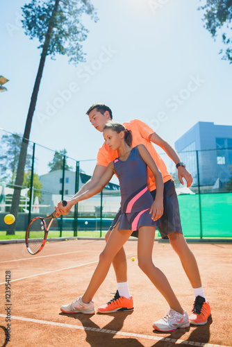 Instructor or coach teaching child how to play tennis on a court indoor © dreamsnavigator