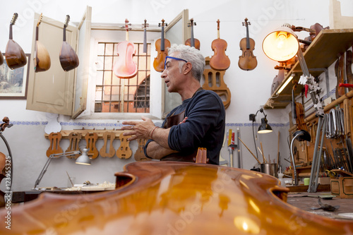 portrait of mature violin maker while testing the violins in his