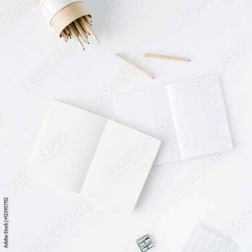 clean blank sketchbook, pencils and pencil sharpener on white background. flat lay, top view