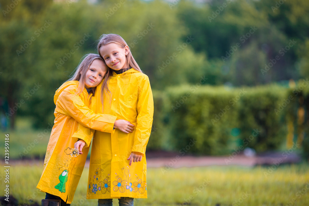 Adorable little girls under the rain on warm autumn day Adorable little girls under the rain on warm autumn day