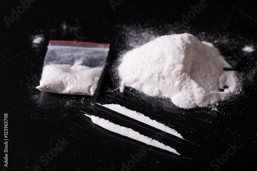 Plastic packet, two lines and pile of cocaine on black backgroun photo