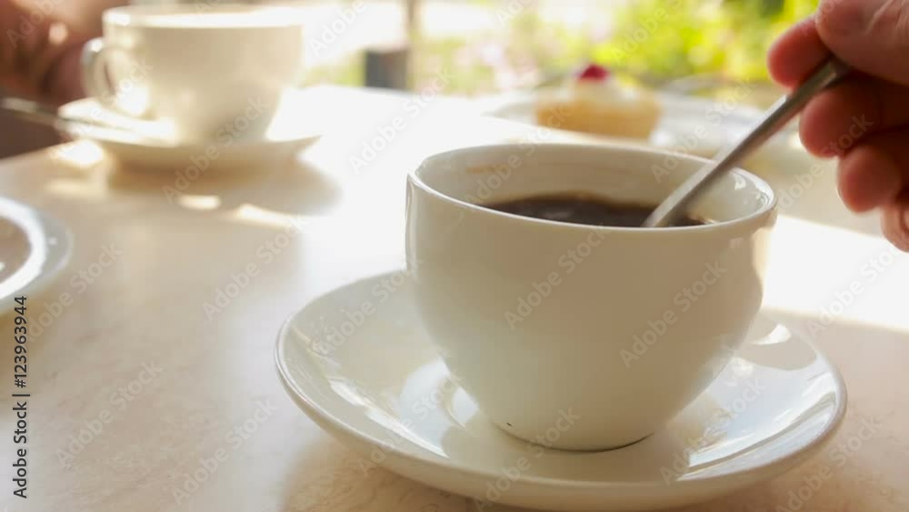 Hand Stirring Steaming Cup of Black Coffee. coffee house