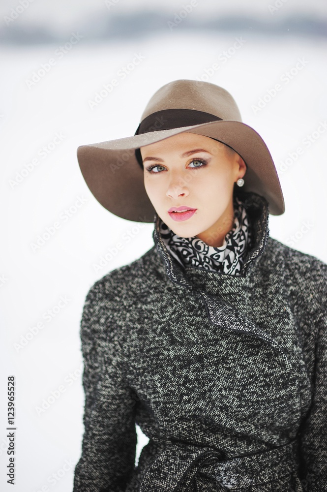 Beautiful elegant girl in a hat outside on a snowy white backgro Beautiful elegant girl in a hat outside on a snowy white backgro