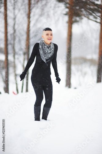 Young pretty smiling girl enjoys the falling snow in winter Park.