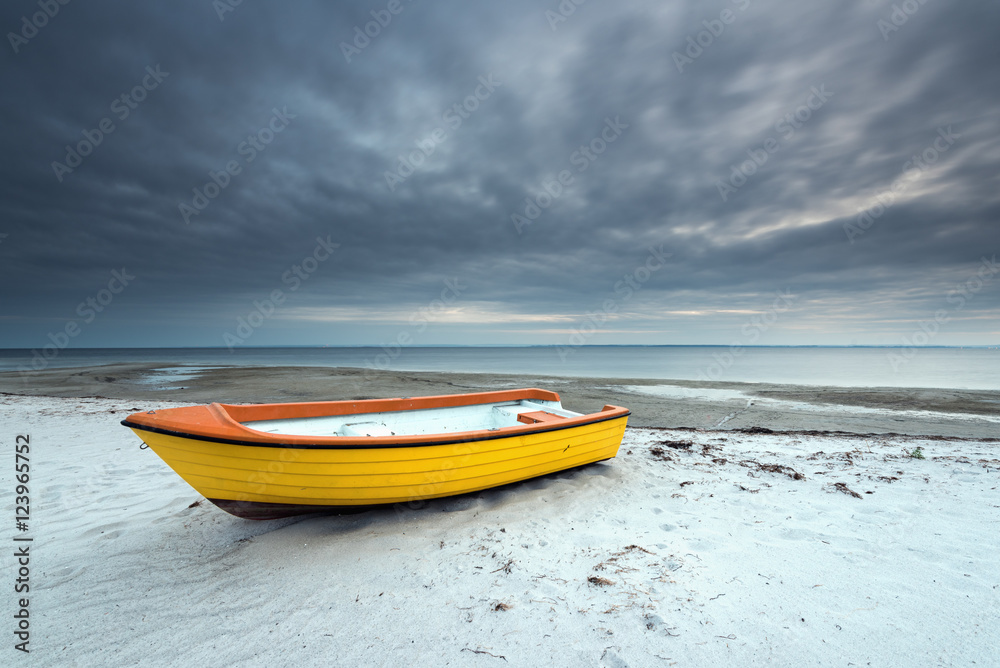 Alone boat on the sandy beach in cloudy day. Baltic Sea. Poland.