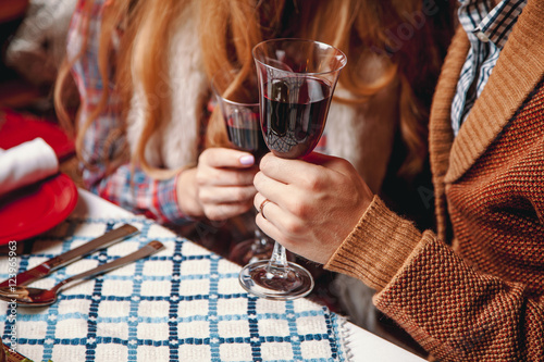 Beautiful couple sitting at the laid table for thanksgiving day, holding glass of wine in the hands