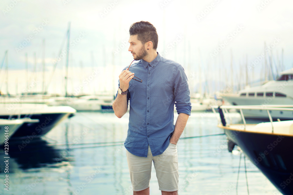 Portrait of young bearded handsome man with luxury yachts in port. Portrait of young bearded handsome man with luxury yachts in port.