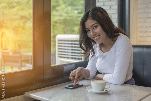 Beautiful young woman Playing Mobile with morning coffee