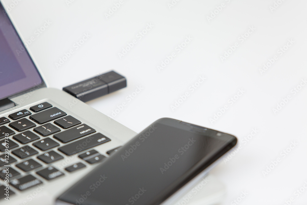 usb stick plugged and smartphone on top of laptop usb stick plugged and smartphone on top of laptop