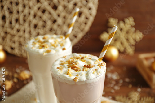 Delicious milkshakes with Christmas decoration on wooden table closeup