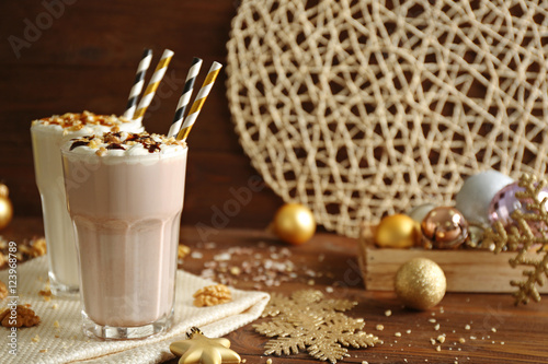 Delicious milkshakes with Christmas decoration on wooden table closeup