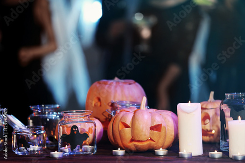 Glass jars, candles and Halloween decor on blurred background