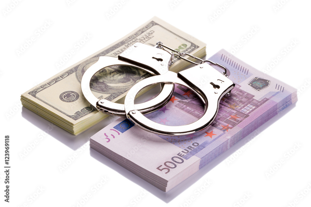 Pair of handcuffs closeup on dollar and euro banknotes stacks Pair of handcuffs closeup on dollar and euro banknotes stacks
