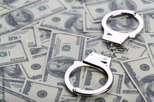 Pair of handcuffs closeup on dollar banknotes background